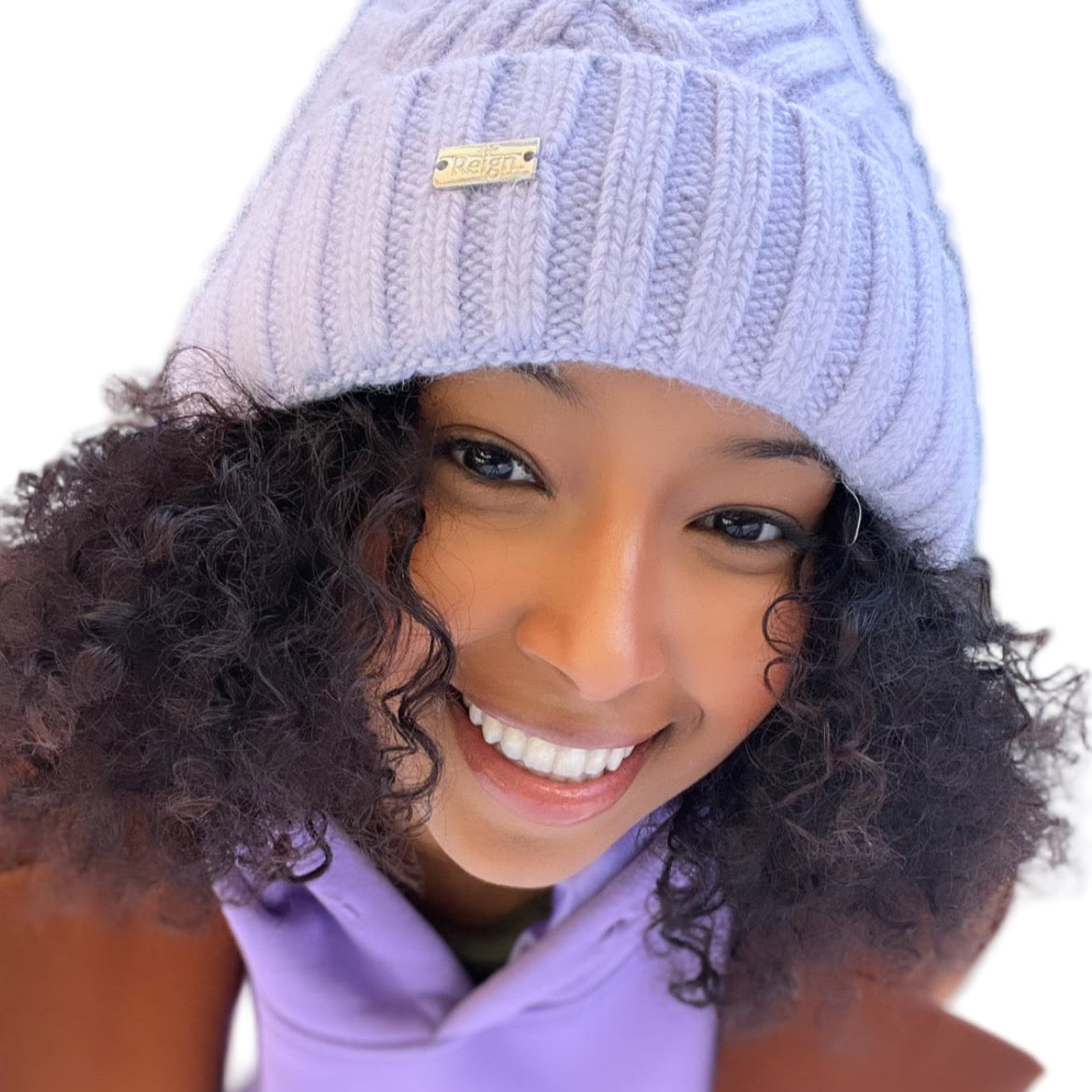 Person wearing a light purple knit hat and matching outfit on a white background